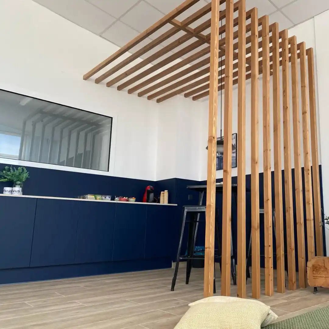 Zona de descanso en el Coworking Rivus con estructura de madera y mesa alta con sillas.