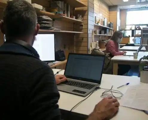Trabajadores en el Centro La Era Coworking usando computadoras en sus escritorios.