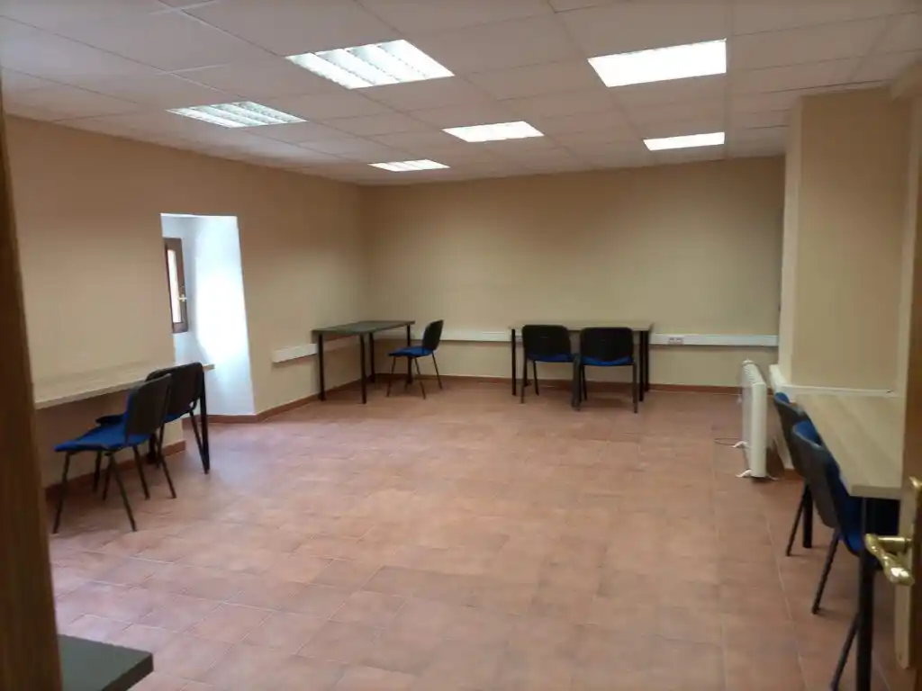 Oficina en el Convento de la Consolación, con mesas, sillas negras y una ventana en el fondo.