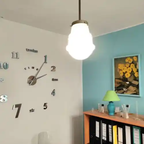 Espacio de trabajo en 'Tu lugar de trabajo' con reloj decorativo, lámpara y estantería de archivadores.