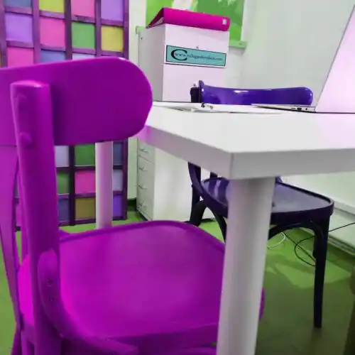 Espacio creativo en 'Tu lugar de trabajo' con sillas moradas y mesas blancas.