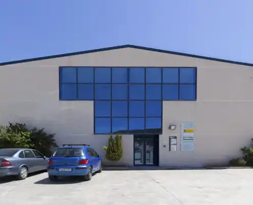 Fachada del Centro Andorra con ventanas grandes y coches estacionados en la entrada.