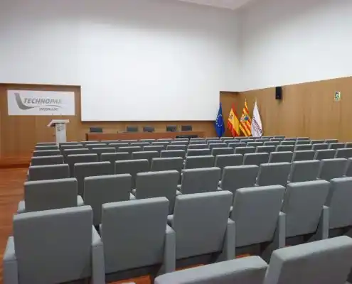 Auditorio en Technopark con asientos cómodos, área de conferencias y banderas de varias instituciones.