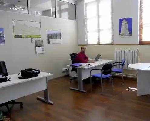 Oficina en el Centro Utebo con escritorios, sillas y una persona trabajando en su computadora.