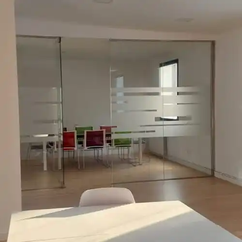 Oficina con puertas de vidrio en coworking con mesa de reuniones.