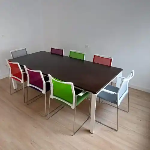 Oficina en coworking con mesas y sillas de colores brillantes.