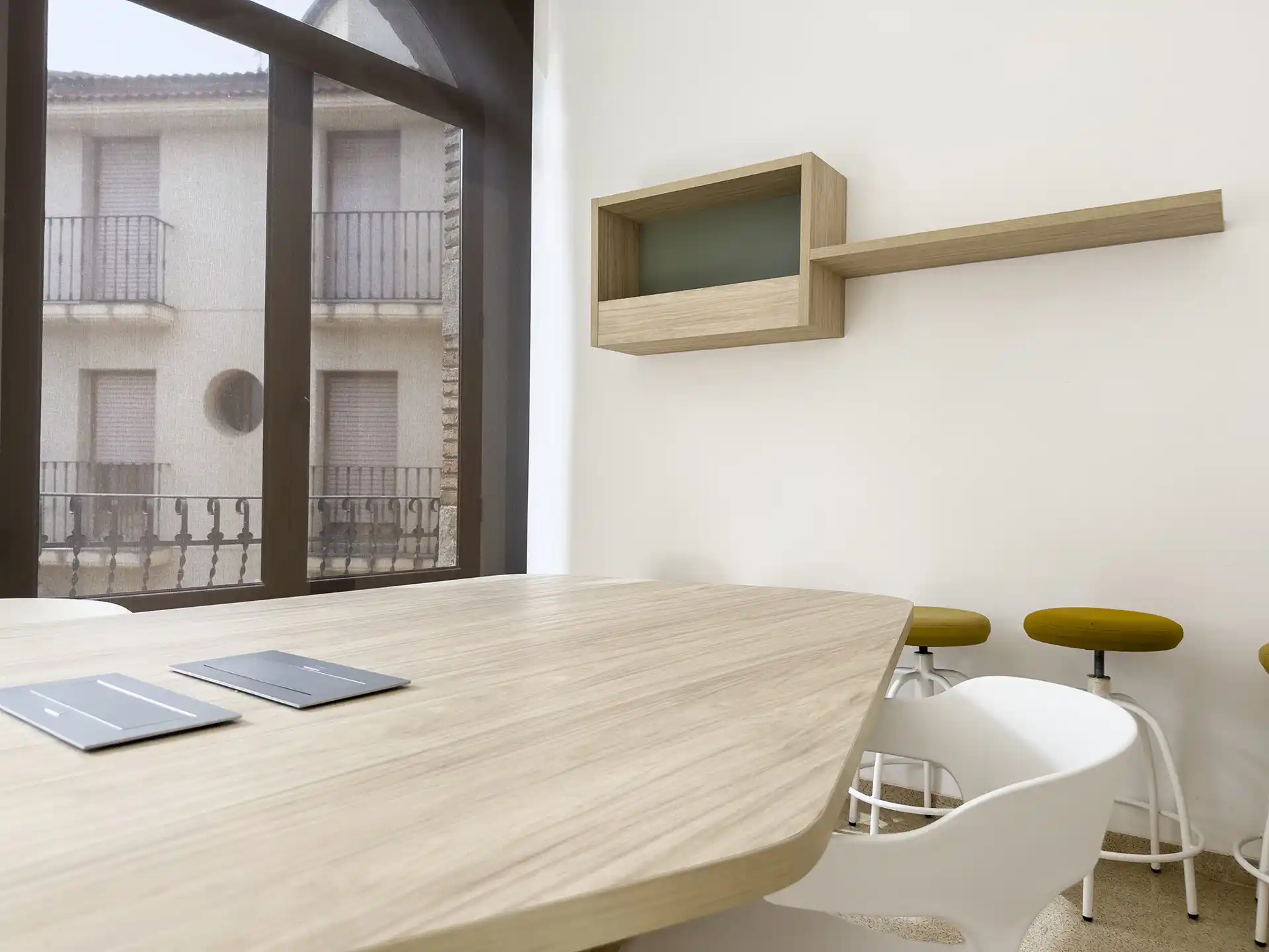 Detalle de mesa de trabajo con sillas y estantería en Centro de Emprendedores.