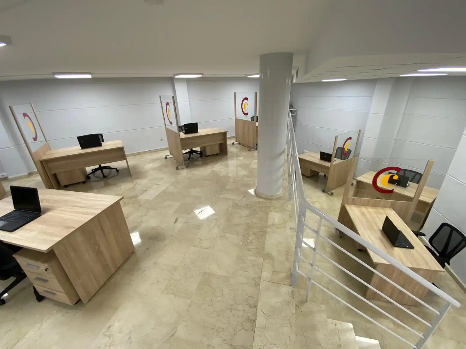 Oficina con mesas de trabajo y sillas negras en el centro de coworking