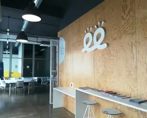 Zona de recepción del Centro Sofejea, destacando el logo en la pared de madera y el área de espera con mesas.