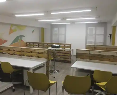 Vista de la sala de reuniones del Centro con mesas blancas y sillas amarillas.