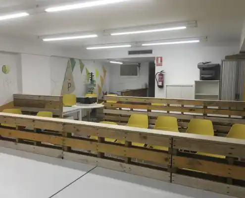 Sala de reuniones del Centro, equipada con mesas blancas y sillas amarillas de diseño moderno.