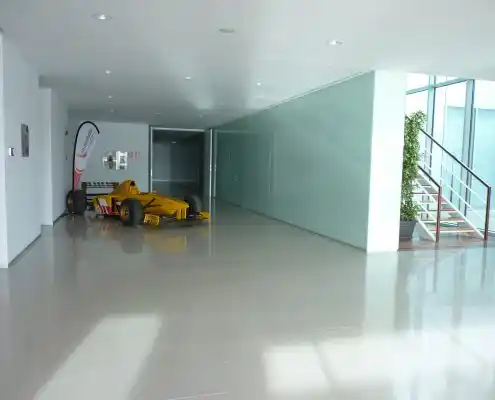 Hall en Technopark con diseño moderno, piso blanco y un automóvil de carreras como decoración.