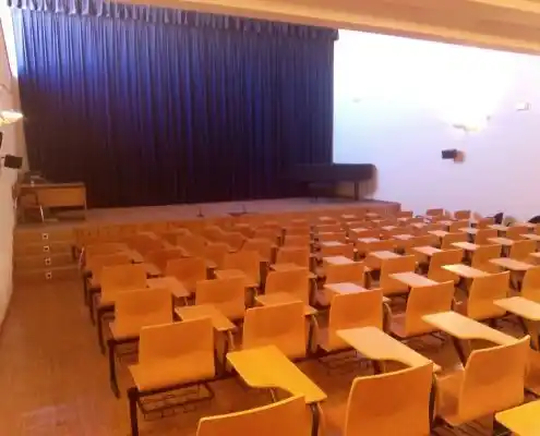 Aula del Centro Maestrazgo, equipada con asientos en filas y un escenario al fondo.