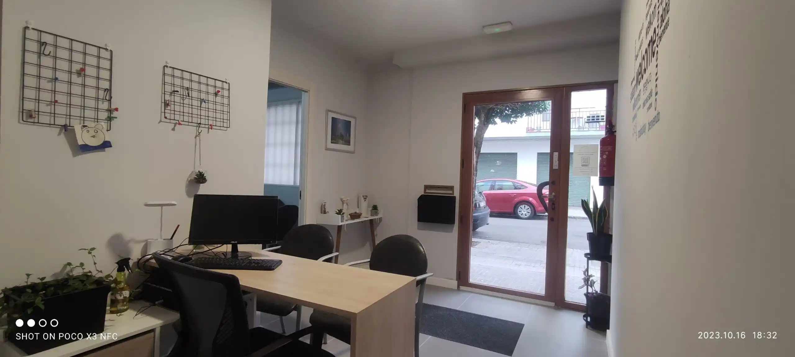 Vista desde el interior del Centro Pirineos, mostrando la puerta principal de vidrio, un escritorio de recibidor y sillas.