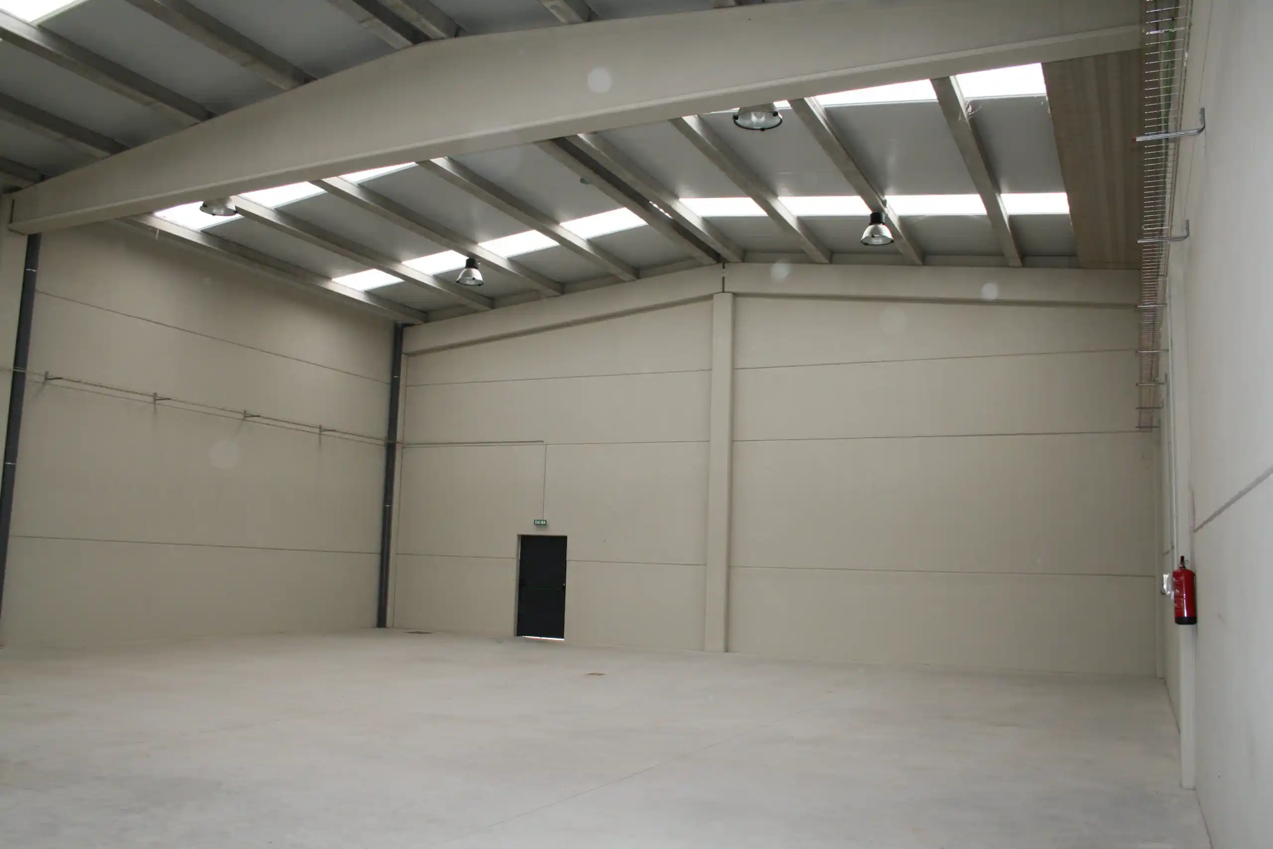Gran espacio industrial con techos altos y puerta de entrada.