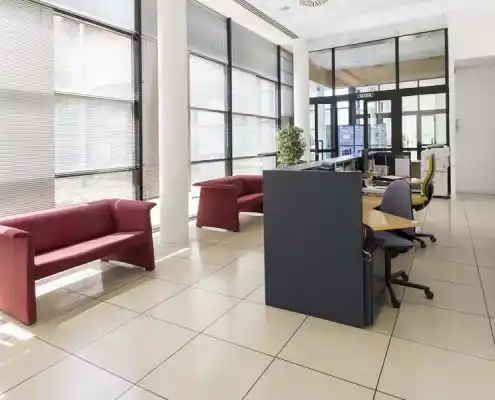 Sala de espera con sillones rojos y oficina al fondo en el Centro Huesca.