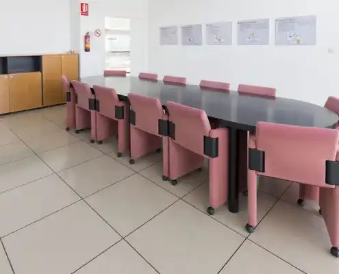Sala de reuniones con mesa grande y sillas rosa en el Centro Huesca.