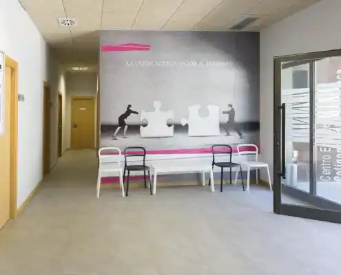 Pasillo en el Centro Barbastro con bancos y mural inspirador en la pared.