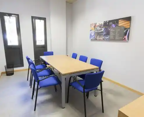 Oficina en el Centro Barbastro con mesa de trabajo y sillas azules.