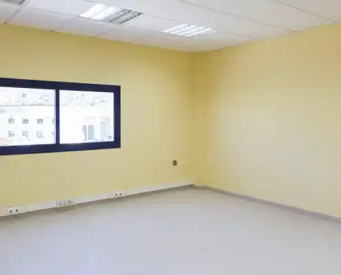 Oficina vacía en el Centro Andorra con ventana y paredes de color amarillo.