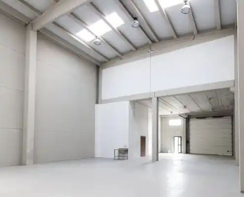 Vista del interior de la nave en el centro Mequinenza con luz natural y techo alto.