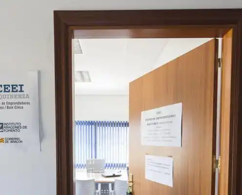 Puerta de entrada a oficina en el centro Mequinenza con señalización exterior.