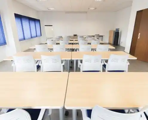 Sala de reuniones en el centro Mequinenza con mesas y sillas dispuestas para capacitación.