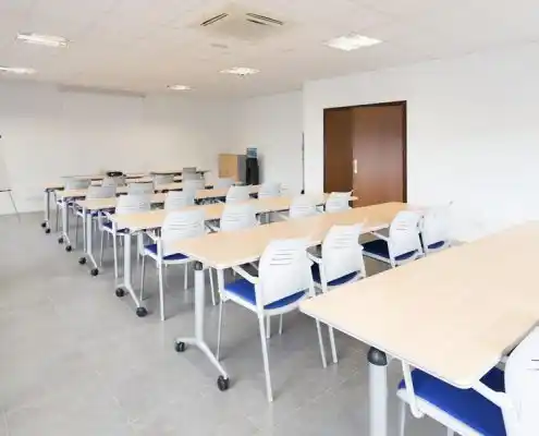 Sala de reuniones del centro Mequinenza con mesas modulares y sillas ergonómicas.