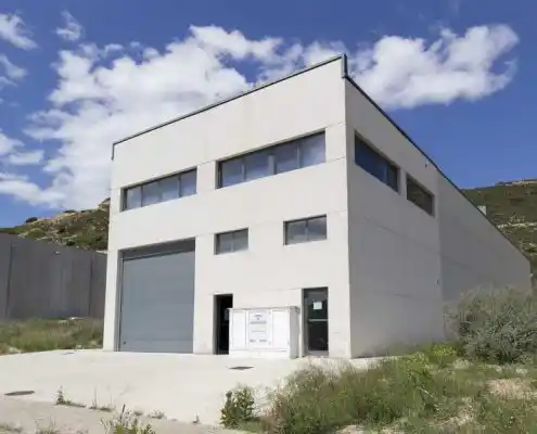 Fachada exterior del centro Mequinenza con puerta de carga y ventanales.