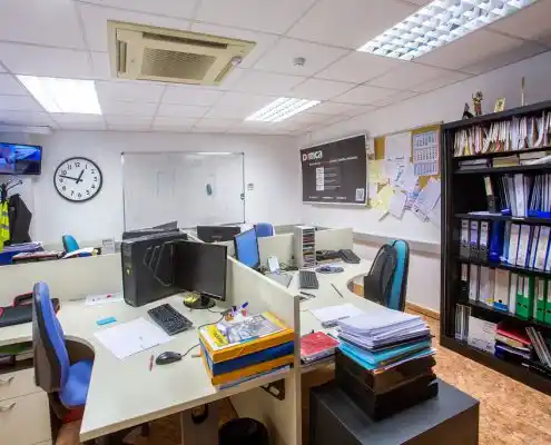 Oficina compartida en el centro de emprendedores de Calatayud con escritorios, computadoras y estanterías llenas de archivos.