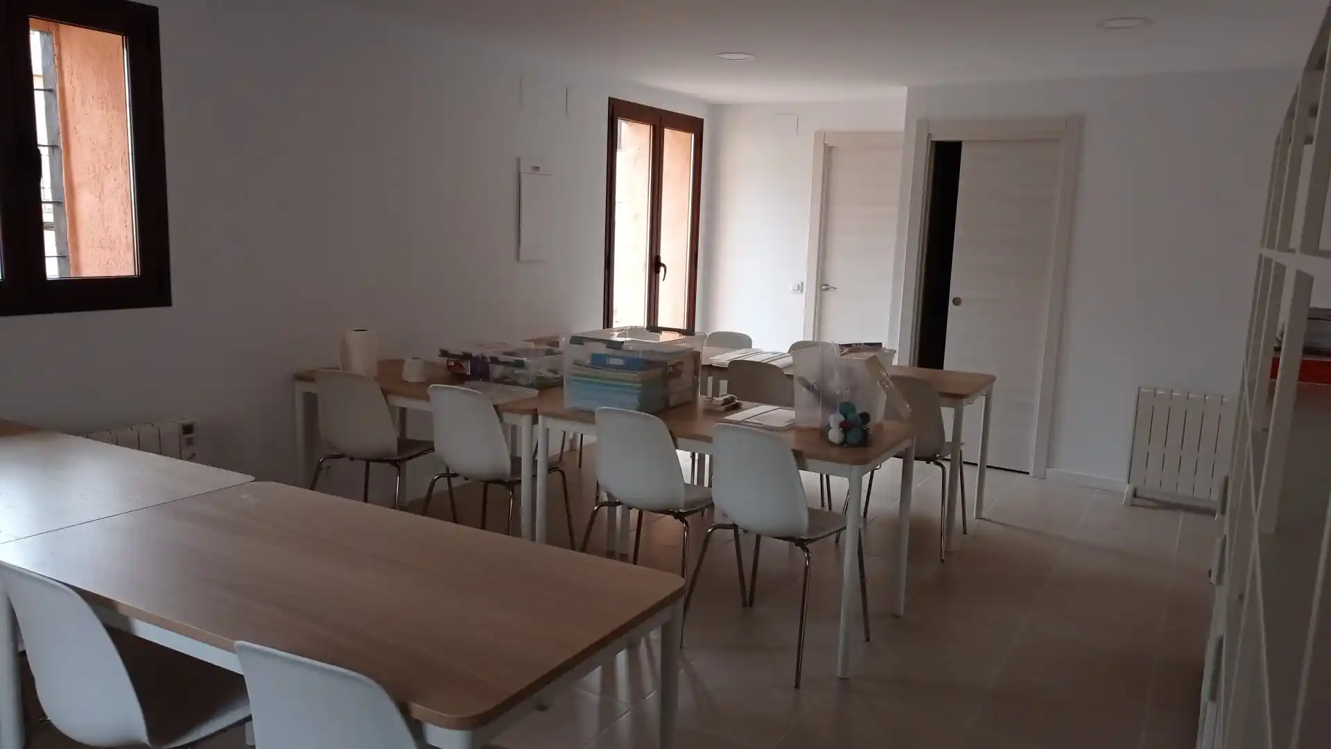 Sala de reuniones con mesas, sillas y una ventana.