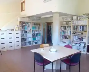 Sala de trabajo en el Centro Maestrazgo, con una mesa, sillas y estanterías llenas de material de oficina.