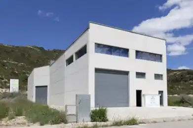 Fachada principal del centro Mequinenza con entrada para vehículos y ventanales amplios.