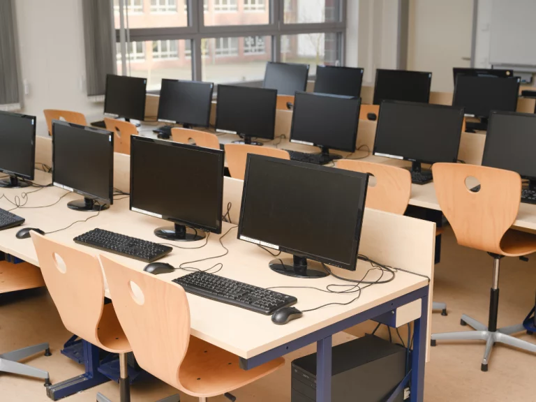 Oficina luminosa en el Centro Ooo Zaragoza, equipada con mesas, sillas y varias computadoras, creando un ambiente de trabajo moderno y funcional.