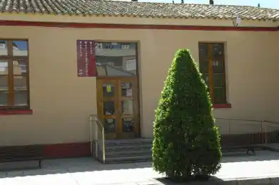 Fachada exterior del Centro Utebo, con puerta de madera, ventanas y una planta decorativa en el exterior