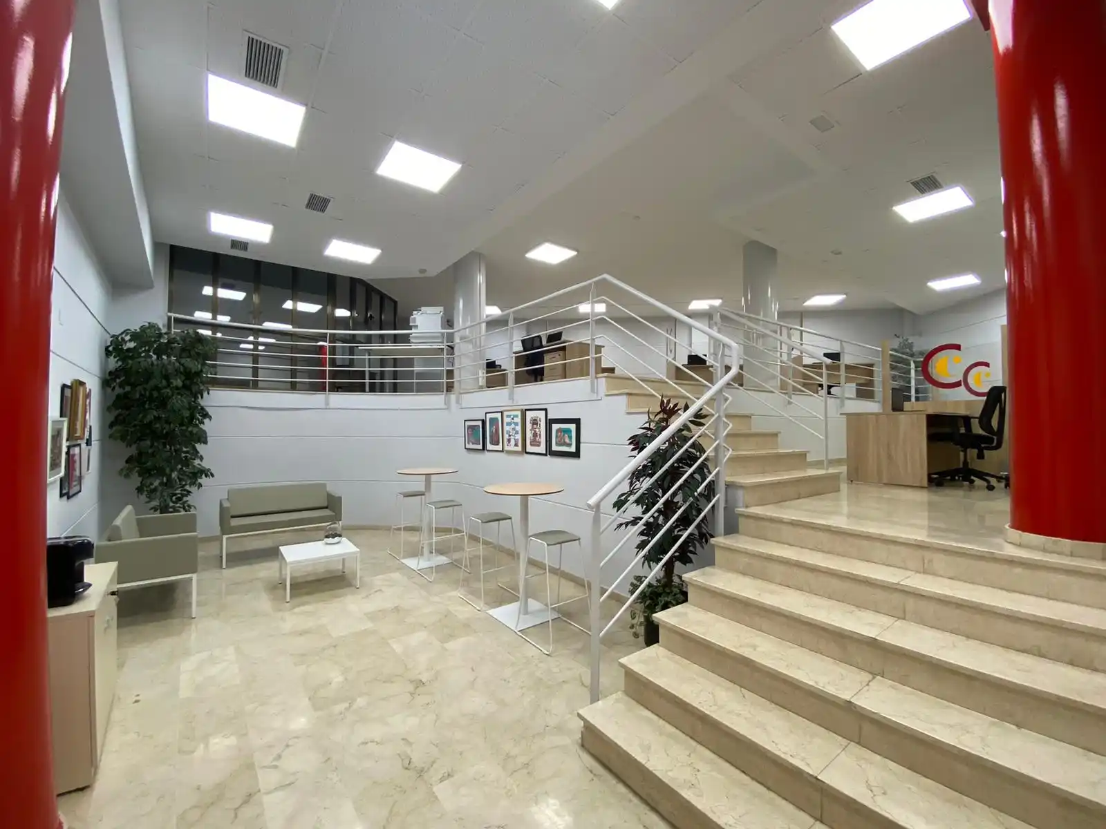 Zona común con escaleras, mesas y decoración moderna en la Cámara de Teruel