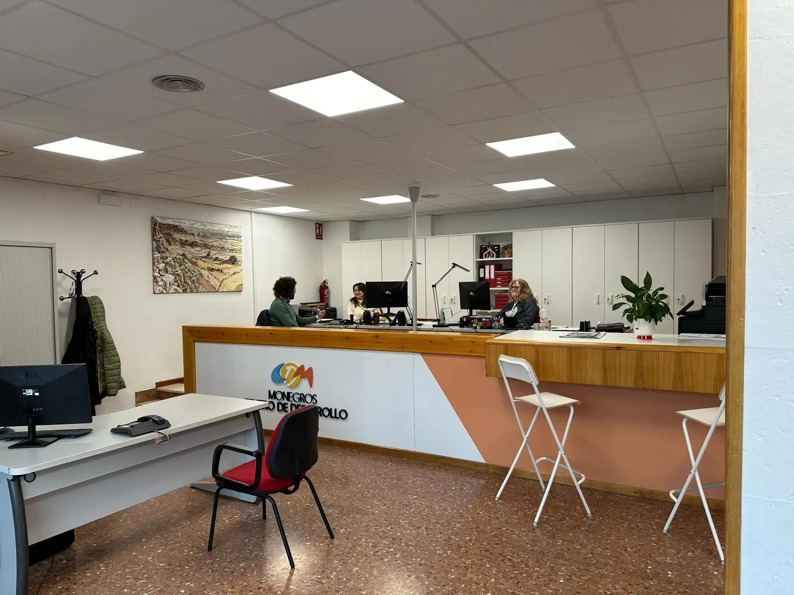 Interior de la oficina del Centro Ceder Monegros, mostrando un espacio de atención al cliente con varias personas trabajando.