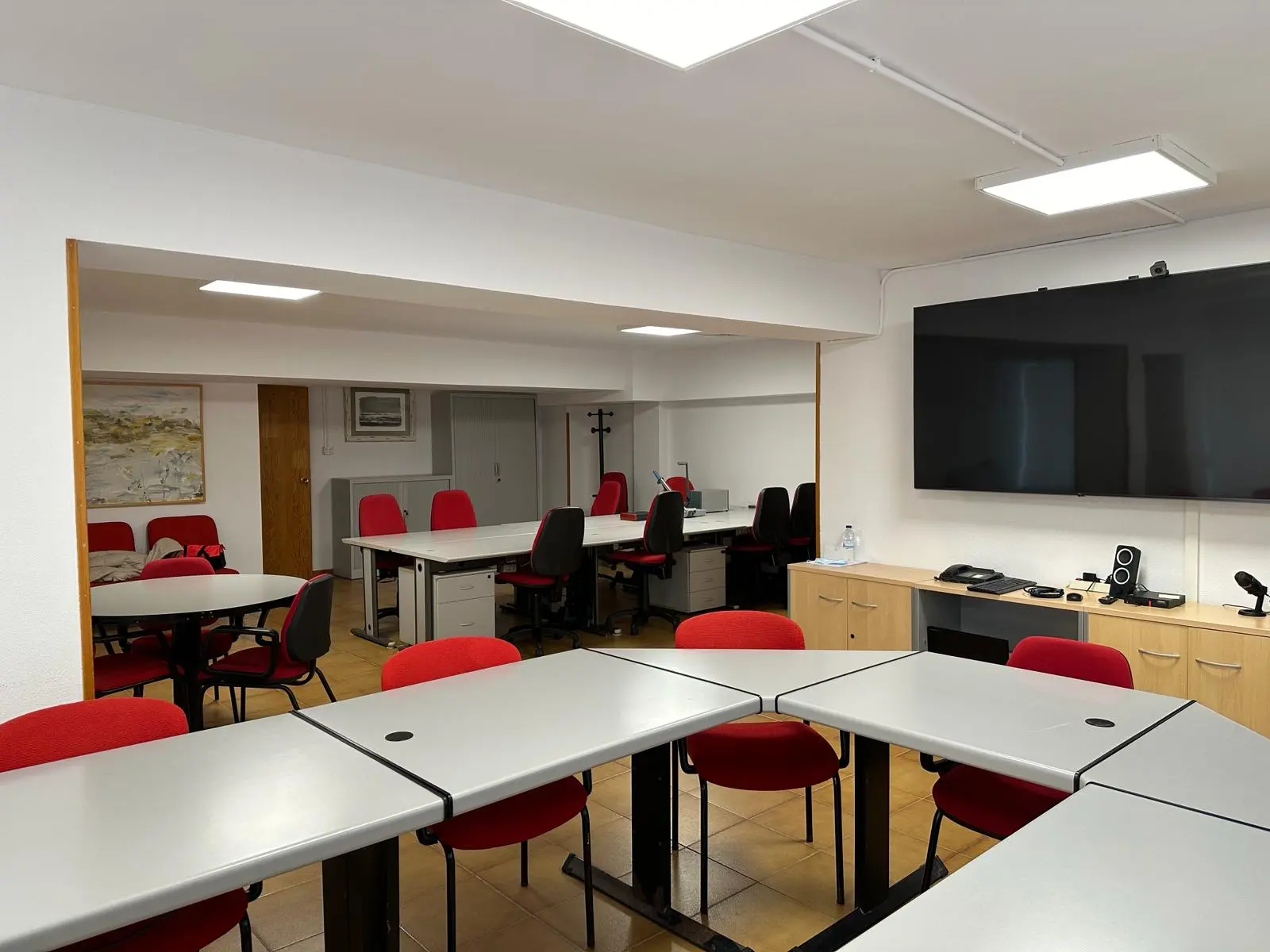 Área de trabajo colaborativo en el Centro Ceder Monegros, con mesas y sillas rojas para un ambiente de trabajo eficiente.