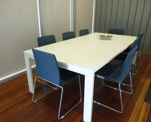 Oficina de reuniones con mesa blanca y sillas modernas de color azul.