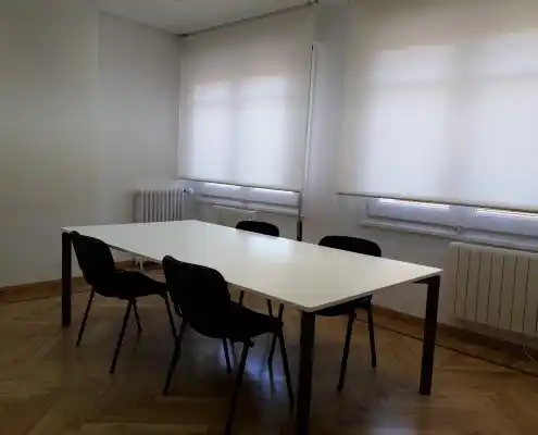 Sala de reuniones con una mesa blanca y sillas alrededor.