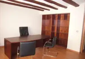 Despacho en la Fundación Campo da Roca, con una mesa de trabajo, sillas y estanterías de madera, ofreciendo un ambiente profesional.