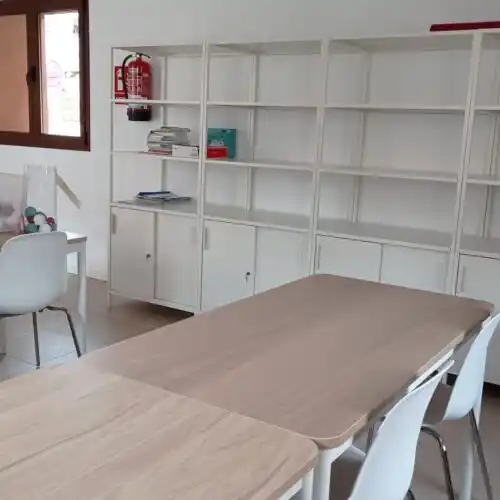 Mesa de trabajo con estanterías blancas y productos varios en el coworking de Moyuela