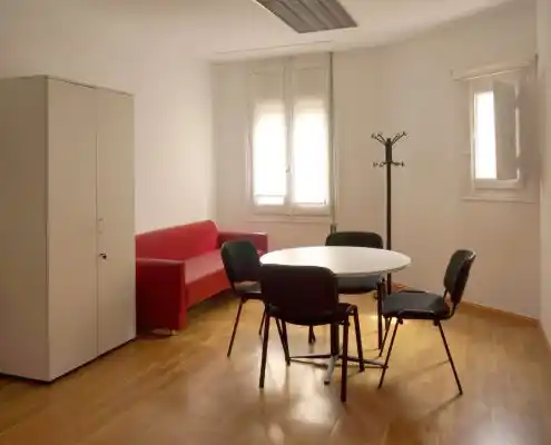 Oficina con muebles de almacenamiento y una mesa para reuniones.