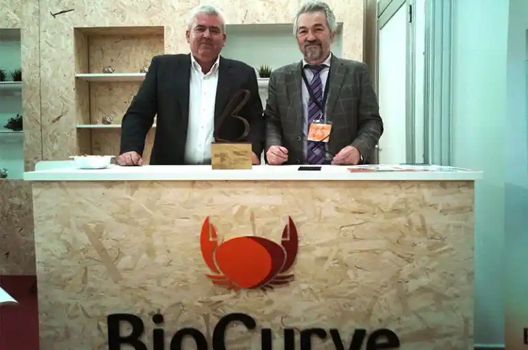Foto de los representantes de BioCurve en su stand con un premio de innovación en calderas de biomasa.